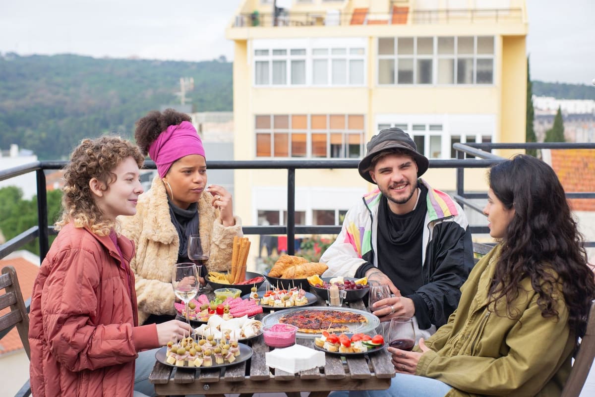 Friends around a long table of food on a rooftop terrace
